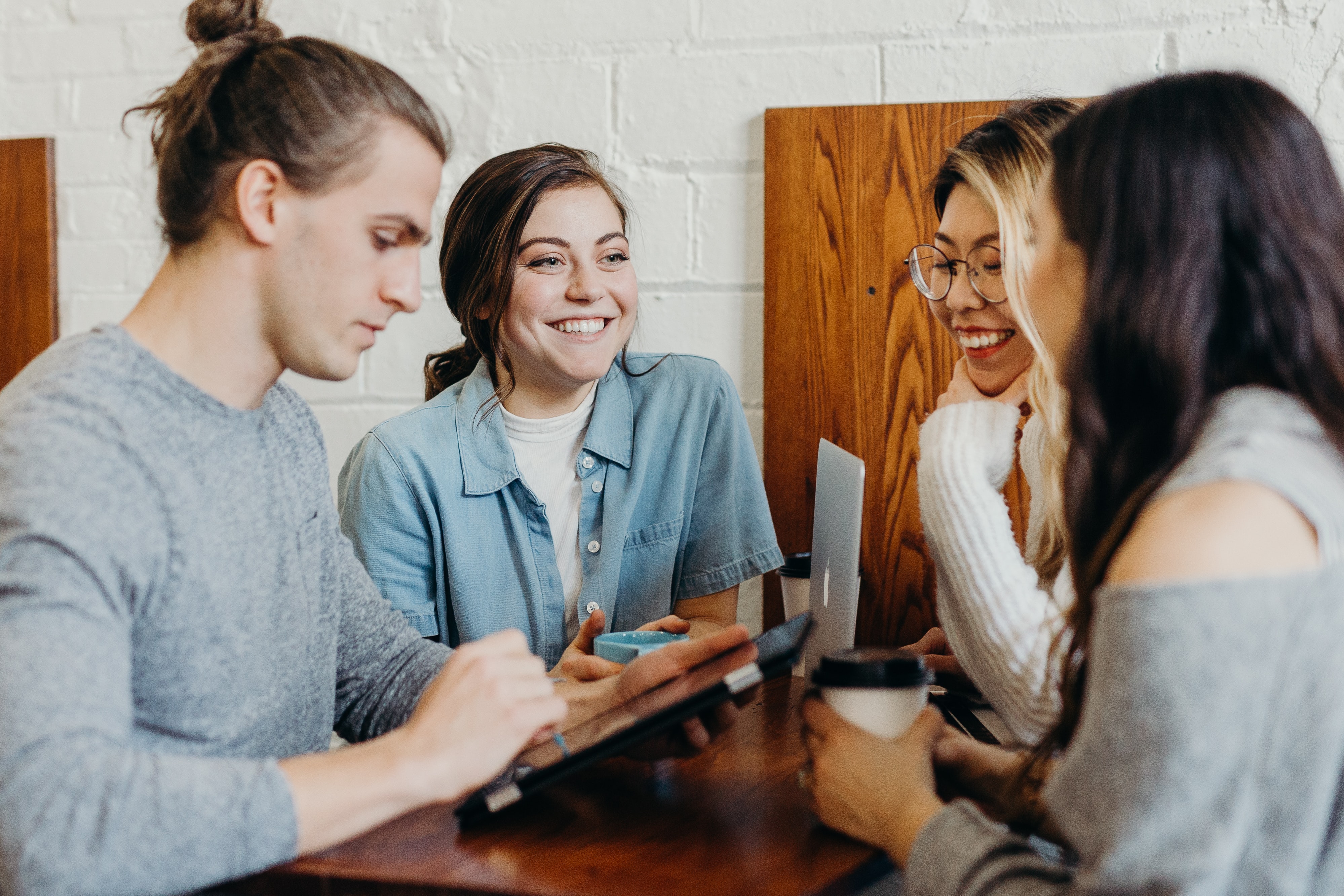 Four people sitting around a table using technology